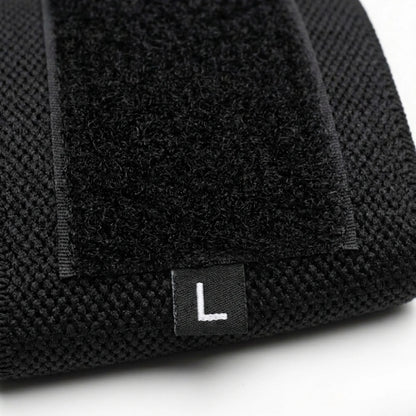 Detalhe da faixa de pulso preta mostrando o fechamento em velcro, a textura do tecido e a etiqueta L